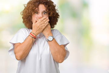 Beautiful middle ager senior woman wearing white t-shirt over isolated background shocked covering mouth with hands for mistake. Secret concept.