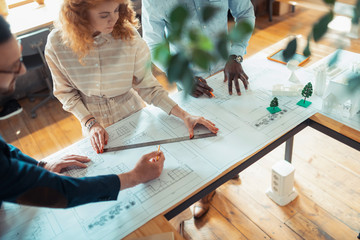 Canvas Print - Curly woman making sketches standing near colleagues