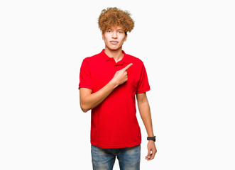 Young handsome man with afro hair wearing red t-shirt Pointing with hand finger to the side showing advertisement, serious and calm face