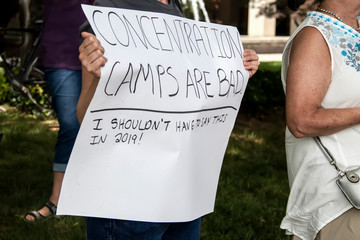 Womans hands holding sign that says concentration camps are bad - I shouldnt have to say this in 2019 - other protesters around - selective focus