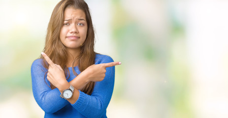 Canvas Print - Young beautiful brunette woman wearing blue sweater over isolated background Pointing to both sides with fingers, different direction disagree