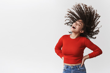 Wall Mural - Energized lively happy good-looking joyful girl curly dark hairstyle waving shaking head curls flying air laughing cheerful dancing having fun showing-off perfect haircut standing white background