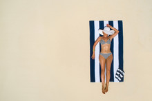 Summer Holiday Fashion Concept - Tanning Girl Wearing Sun Hat At The Beach On A White Sand Shot From Above.Top View From Drone. Aerial View Of Slim Woman Sunbathing Lying On A Beach In Maldives.
