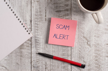 Poster - Handwriting text Scam Alert. Conceptual photo unsolicited email that claims the prospect of a bargain Stationary placed next to a cup of black coffee above the wooden table