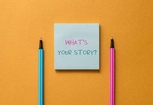 Text sign showing What S Is Your Storyquestion. Business photo showcasing analysisner of asking demonstrating about past life events Front view blank colored sticky note two ballpoints cool yolk