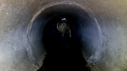 Wall Mural - Sewer tunnel worker going through round sewer tunnel