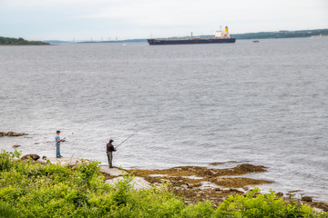 Wall Mural - fishermen by the edge of the ocean fishing