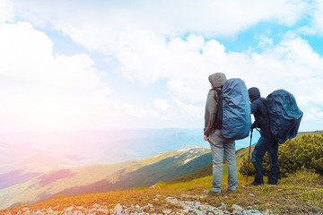 A man rises in the mountains with walking sticks.