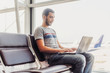 © undrey - Young man using laptop in airport terminal