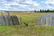 Old Wooden Rickety Fence. Abandoned Field With An Old Wooden Fence. Old Broken Wooden Fence. Summer Sunny Day With Blue Sky And White Clouds. The Effects Of The Hurricane. Disaster