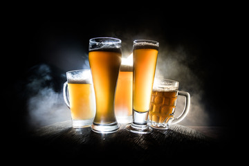 Creative concept. Beer glasses on wooden table at dark toned foggy background.