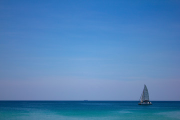  A small sailboat on the sea surface of the water on the horizon of pure blue sky. Beautiful seascape. Serenity.