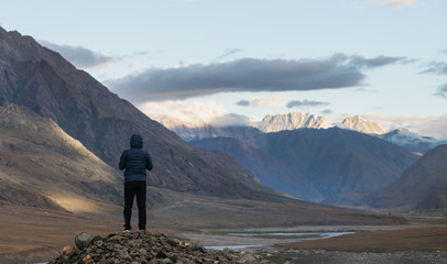 Wall Mural - a man standing on the rock looking at mountains in the morning in india