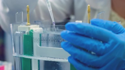 Sticker - A scientist uses a thin pipette to place samples with DNA fragments on an agarose gel to separate DNA fragments.