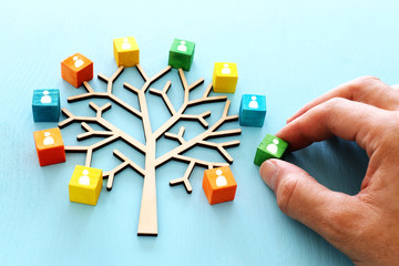 Business image of wooden tree with people icons over blue table, human resources and management concept