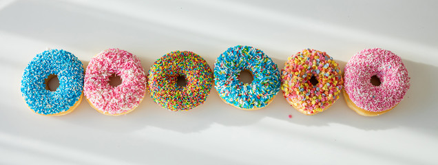 Wall Mural - Doughnuts with colorful decoration on white color background. Top view