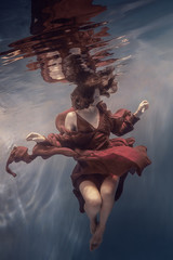 Wall Mural - Girl in a red dress under water