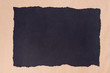 black piece of torn paper on recycled paper background texture