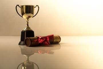 Golden trophy and graduation scroll on white table.Education concept.