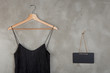 Fashion and shopping concept - blank blackboard and beautiful little black dress on a hanger