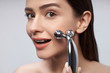 © Yakobchuk Olena - Young woman with smile using platinum face massager