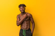 © Asier - Young black man shirtless wearing swimsuit smiling and pointing aside, showing something at blank space.