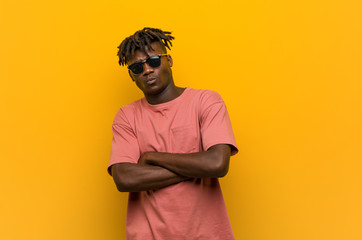 Young casual black man wearing sunglasses frowning face in displeasure, keeps arms folded.