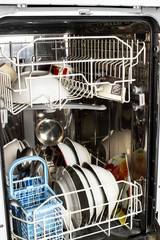 Dishwasher detail. An opened dishwasher with trays extended, lightly loaded. Inside A Dishwasher