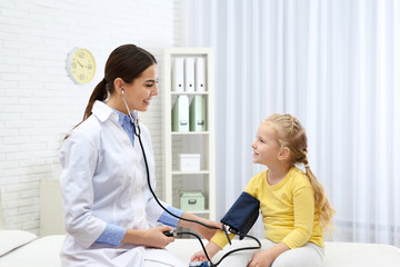 Canvas Print - Little girl visiting doctor in hospital. Measuring blood pressure and checking pulse