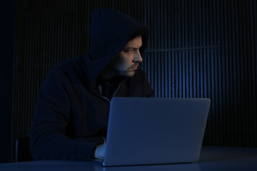 Canvas Print - Man using laptop in dark room. Criminal offence