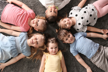 Sticker - Playful little children lying on carpet indoors, top view