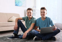 Teenage Twin Brothers Using Laptop Together In Living Room