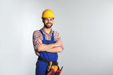Fototapeta  - Portrait of construction worker with tool belt on light background. Space for text