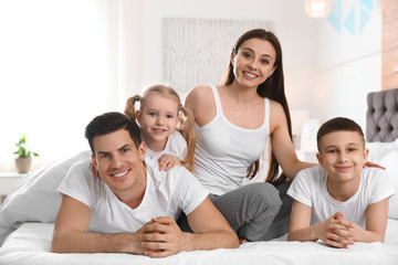 Canvas Print - Happy young family together on large bed