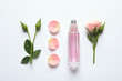 Composition with rose essential oil and flowers on white background, top view