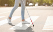 Blind person with long cane crossing road, closeup
