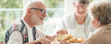 Happy Seniors Sharing Cake During Coffee Meeting At Nursing Home