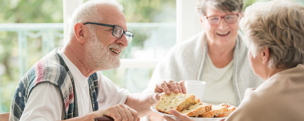 Happy seniors sharing cake during coffee meeting at nursing home