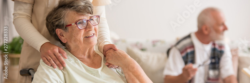 Fotografía Panoramic view of elderly lady on wheelchair holding hands with supporting volun