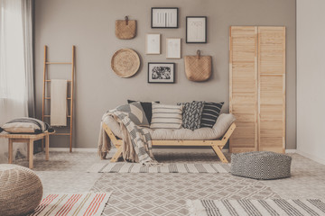 Stylish living room interior design with scandinavian settee, grey wall and natural accents