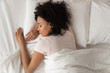 Healthy serene african girl sleeping in comfortable bed, top view