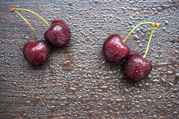 Juicy sweet cherry with water drops on a brown wooden board