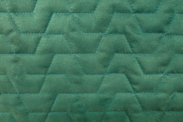 abstract background of green velour quilted fabric close up