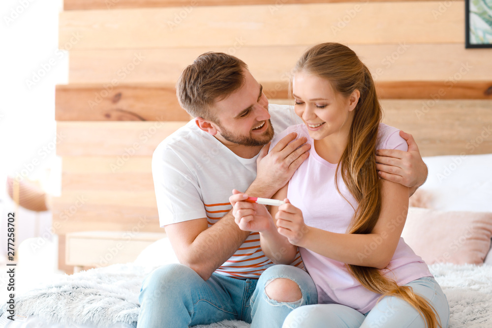 Happy couple with pregnancy test at home