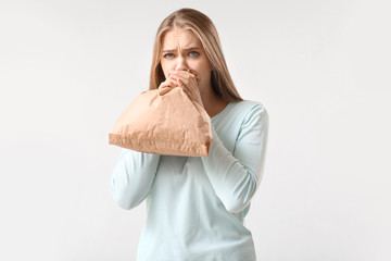 Wall Mural - Woman with paper bag having panic attack on white background