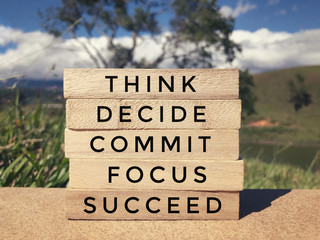 Motivational and inspirational wording - Think, Decide, Commit, Focus, Succeed written on wooden blocks. Blurred styled background.