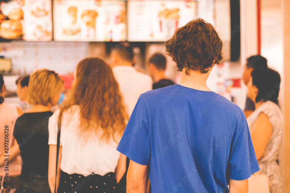young teenager standing in a queue to receive the fastfood package - obrazy, fototapety, plakaty 