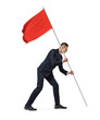 © gearstd - Side full length view of a young serious businessman planting a red flag on white background.