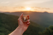 Female Hand With Compass In Summer Mountains At Sunrise, Pov.
