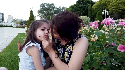 slow motion: young mother tries to cheer up her daughter and hugs in the park